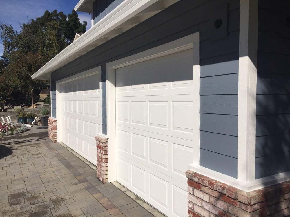 A blue and white house with two white garage doors.