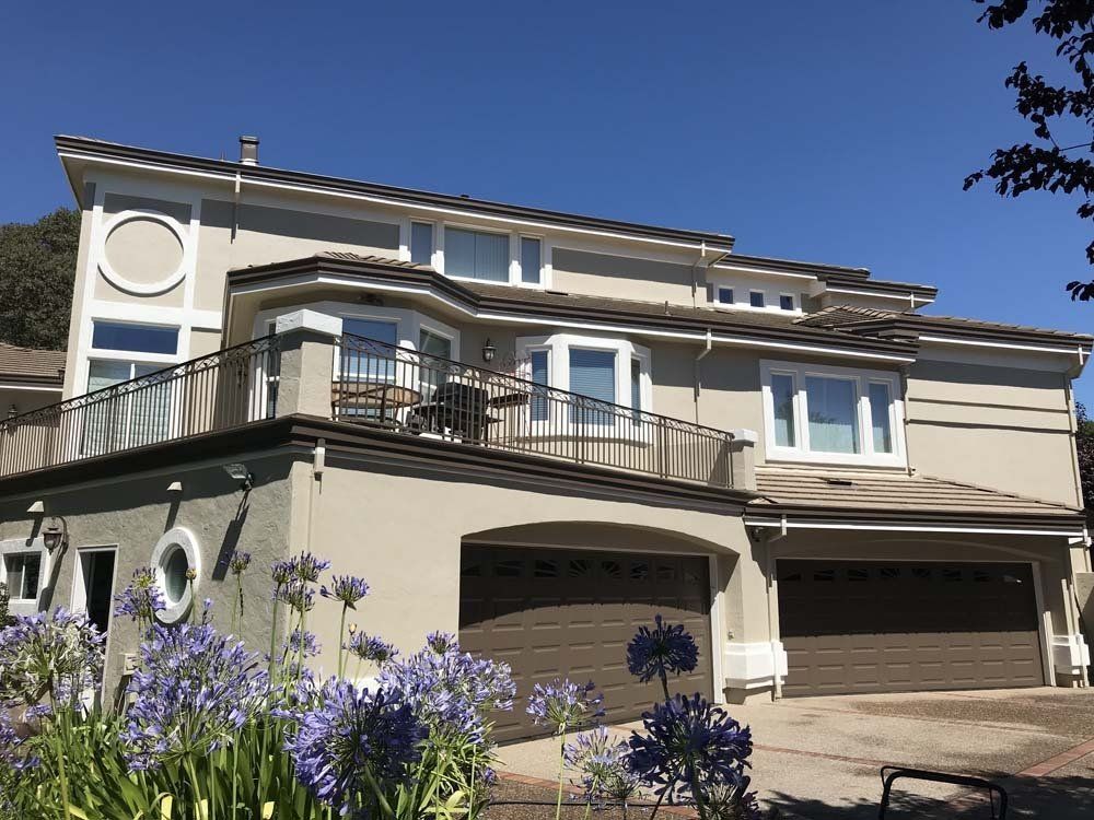 A large house with purple flowers in front of it