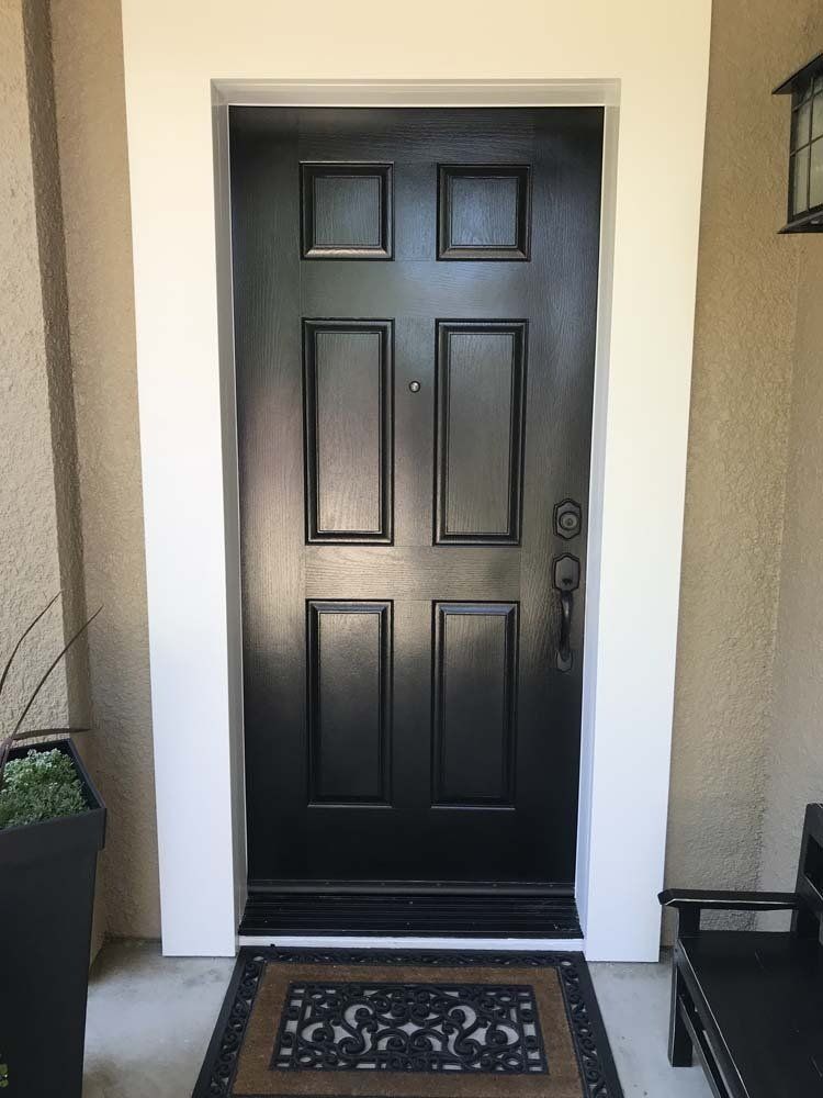 A black door with a white trim is sitting on a porch.