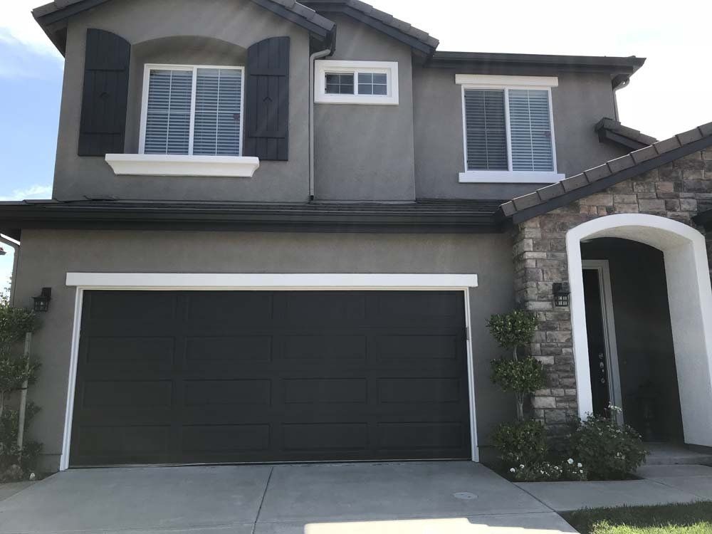 A large house with a black garage door and shutters