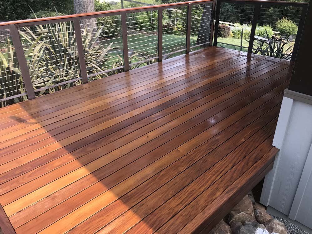 A wooden deck with a metal railing and steps leading up to it.