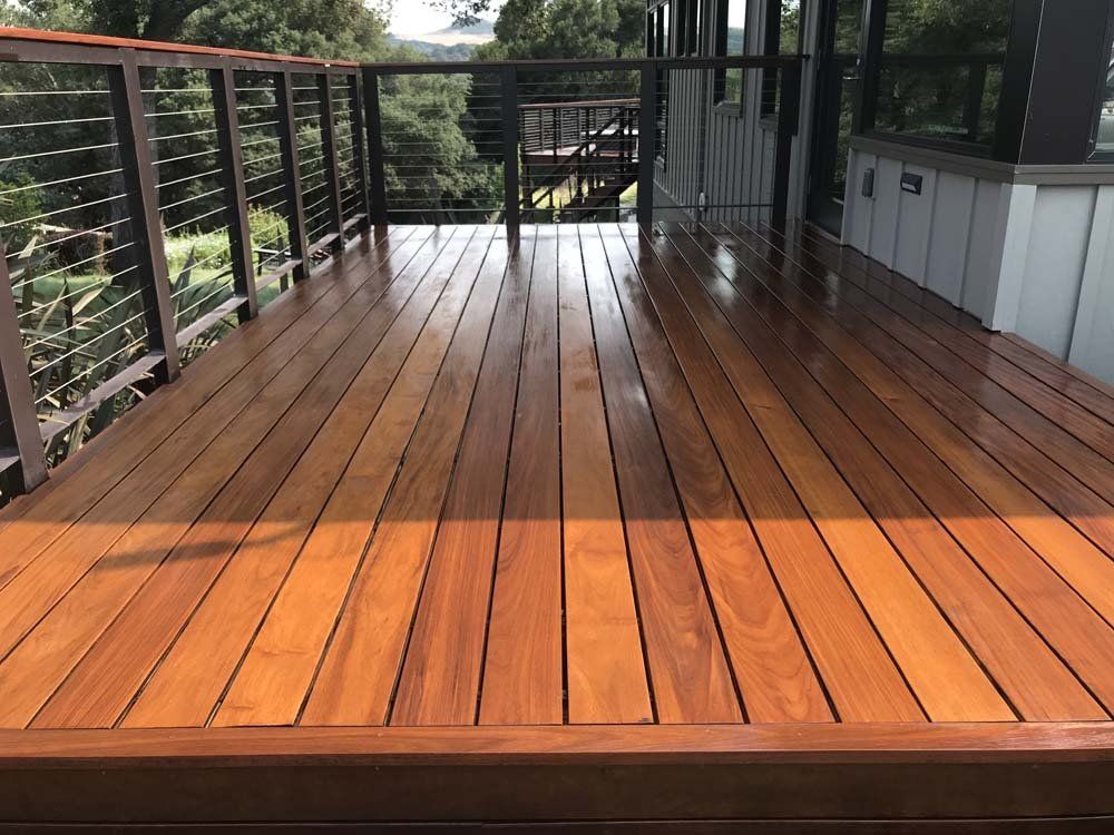 A wooden deck with a metal railing and stairs leading up to it.