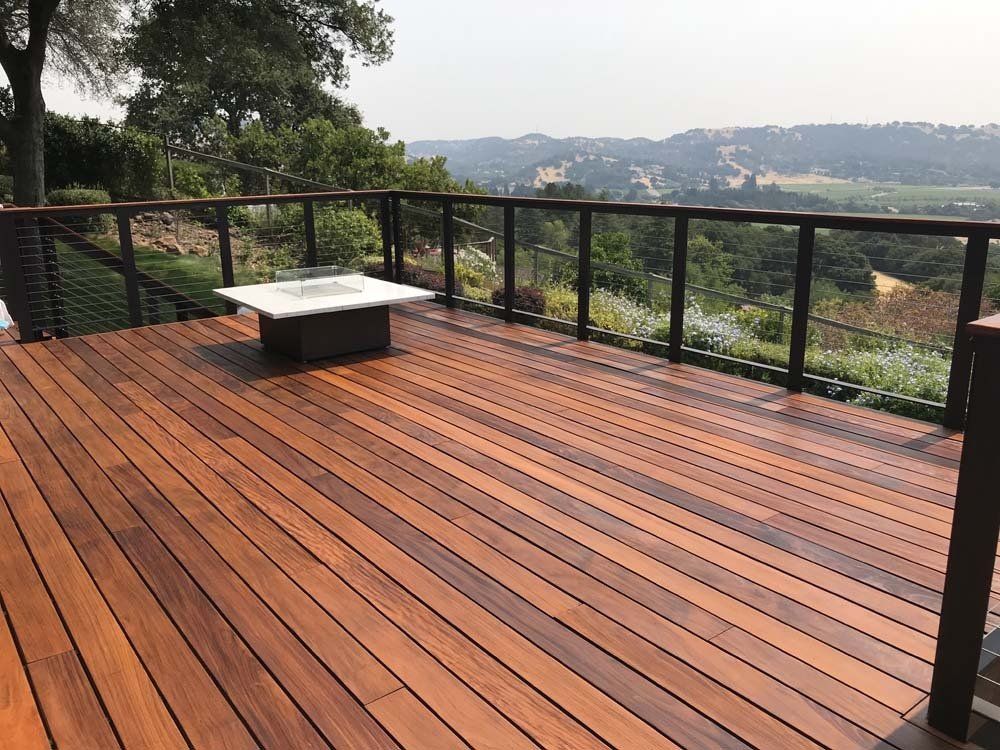 A wooden deck with a fire pit and a view of a hillside.