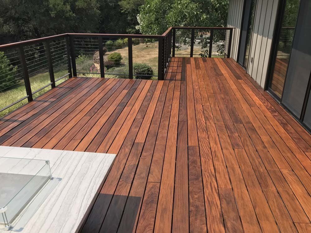 A wooden deck with a black railing and a fireplace