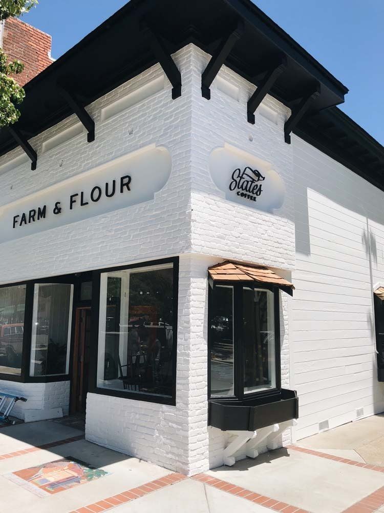 A white brick building with a sign that says farm & flour