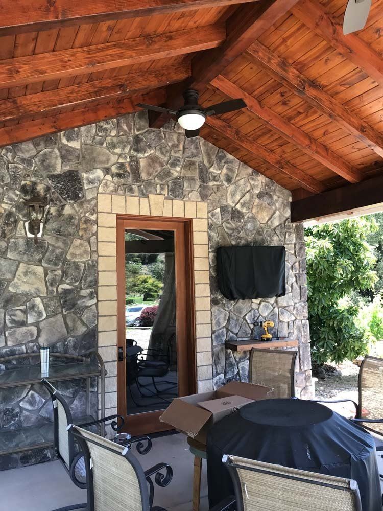 A patio with a fire pit and a ceiling fan