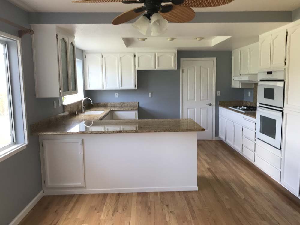 A kitchen with white cabinets and a ceiling fan