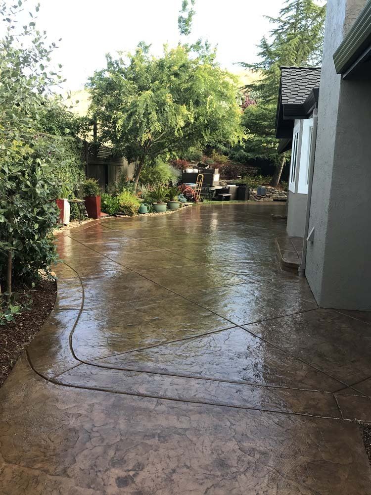 A concrete driveway leading to a house with trees in the background.