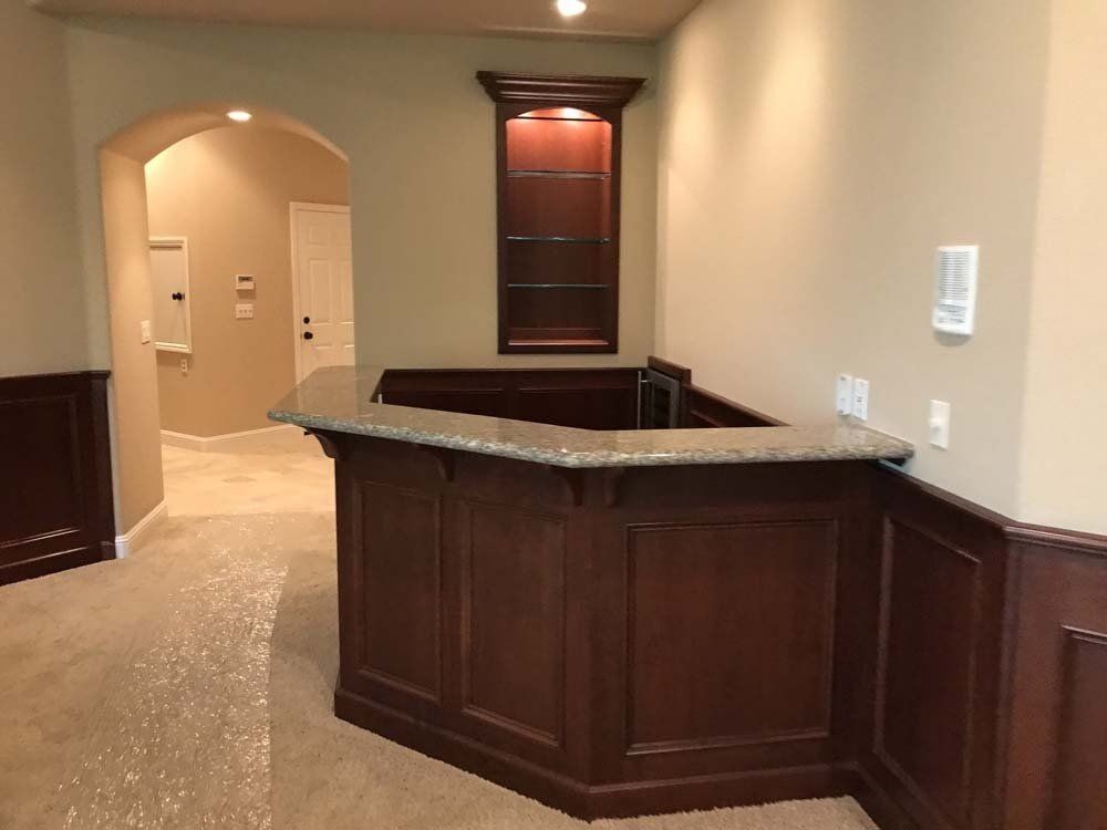 A wooden bar with a granite counter top in a room.