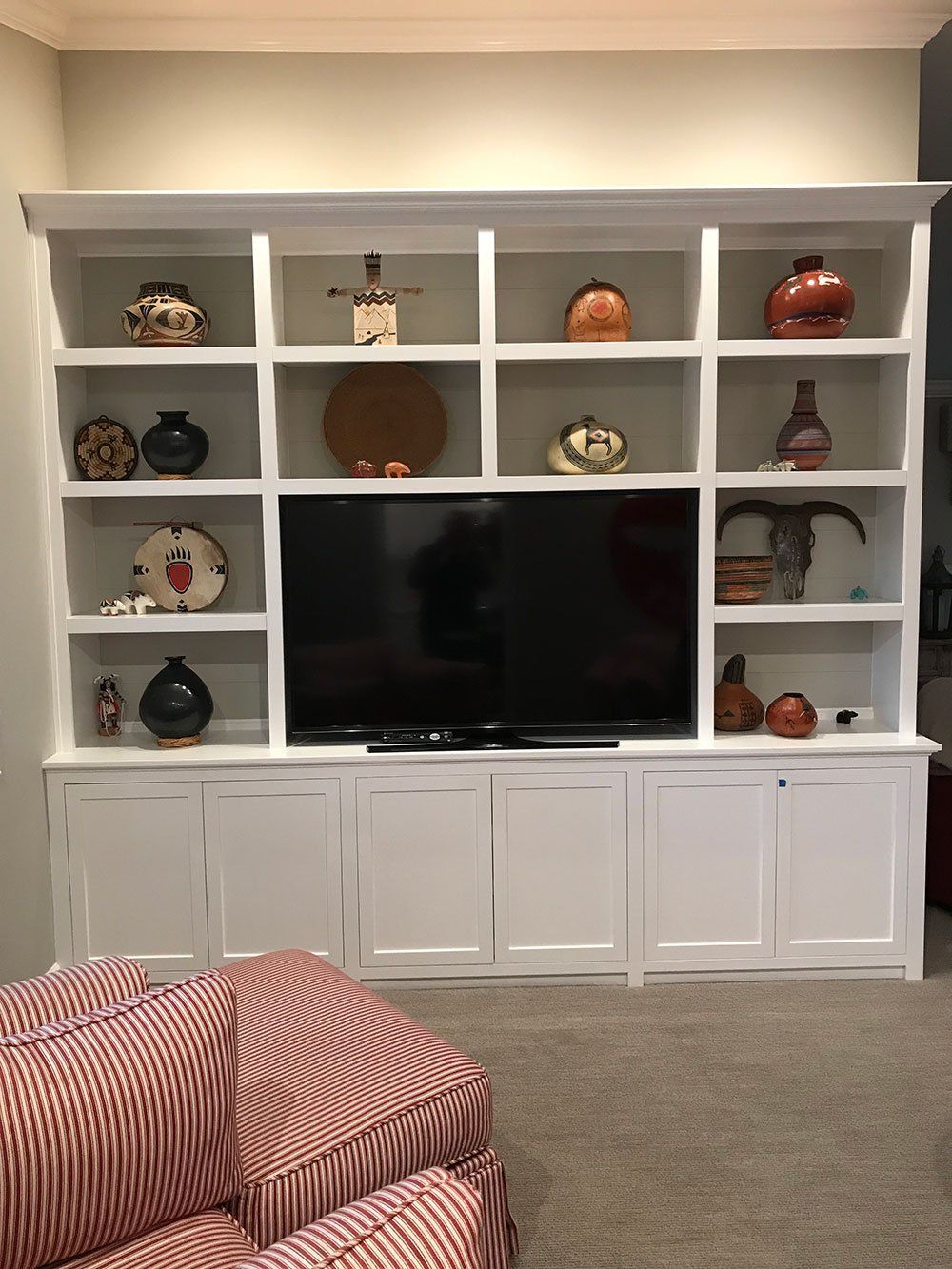 A living room with a couch , shelves , and a flat screen tv.