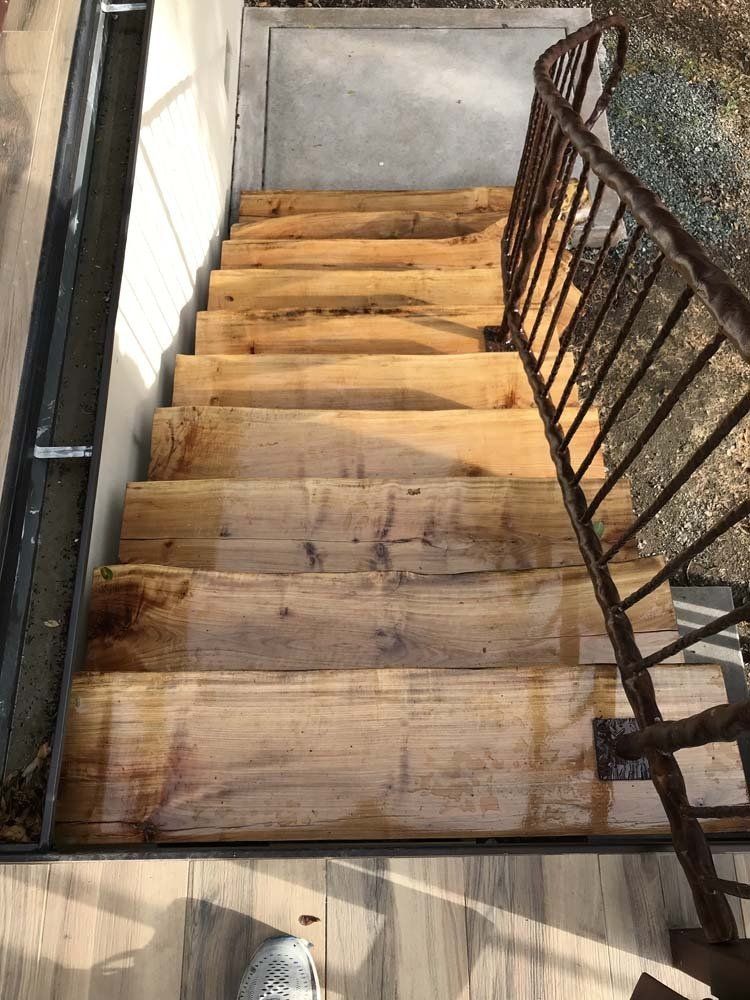 A set of wooden stairs with a metal railing leading up to a building.