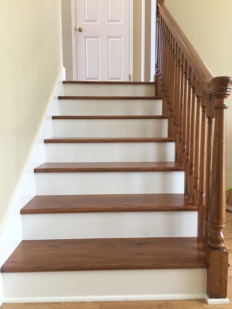 A wooden staircase with white steps and a wooden railing in a house.