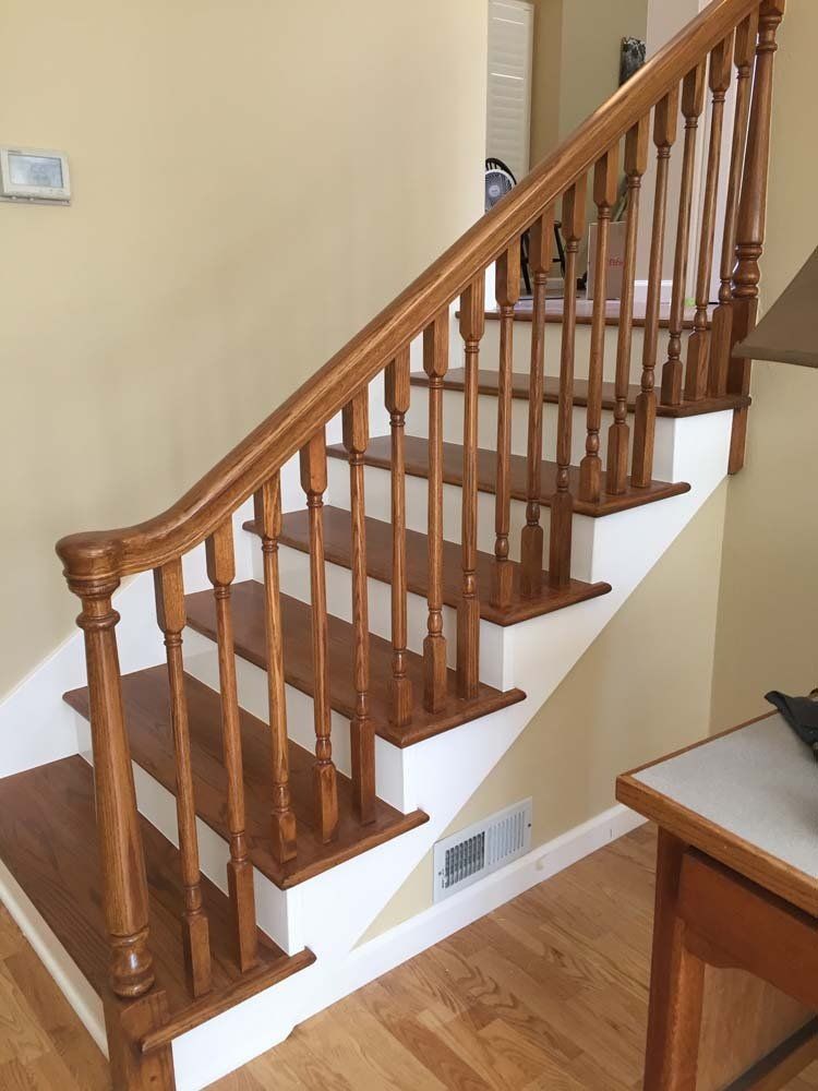 A wooden staircase with white steps and a wooden railing