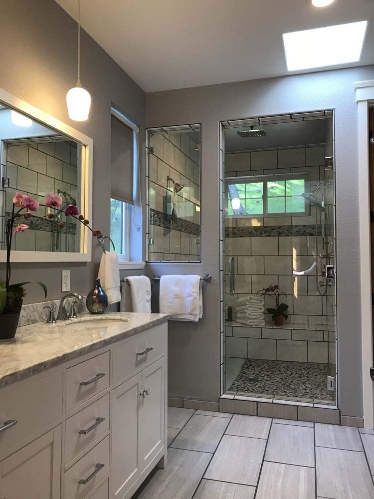 A bathroom with a sink , mirror , and walk in shower.