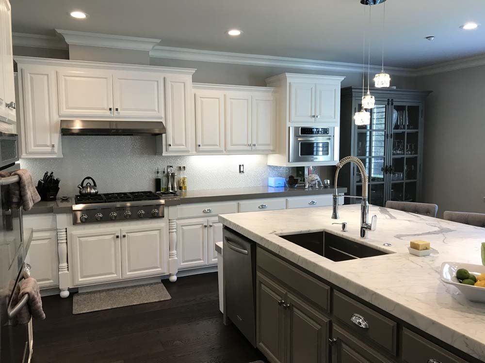 A kitchen with white cabinets , stainless steel appliances , and a large island.