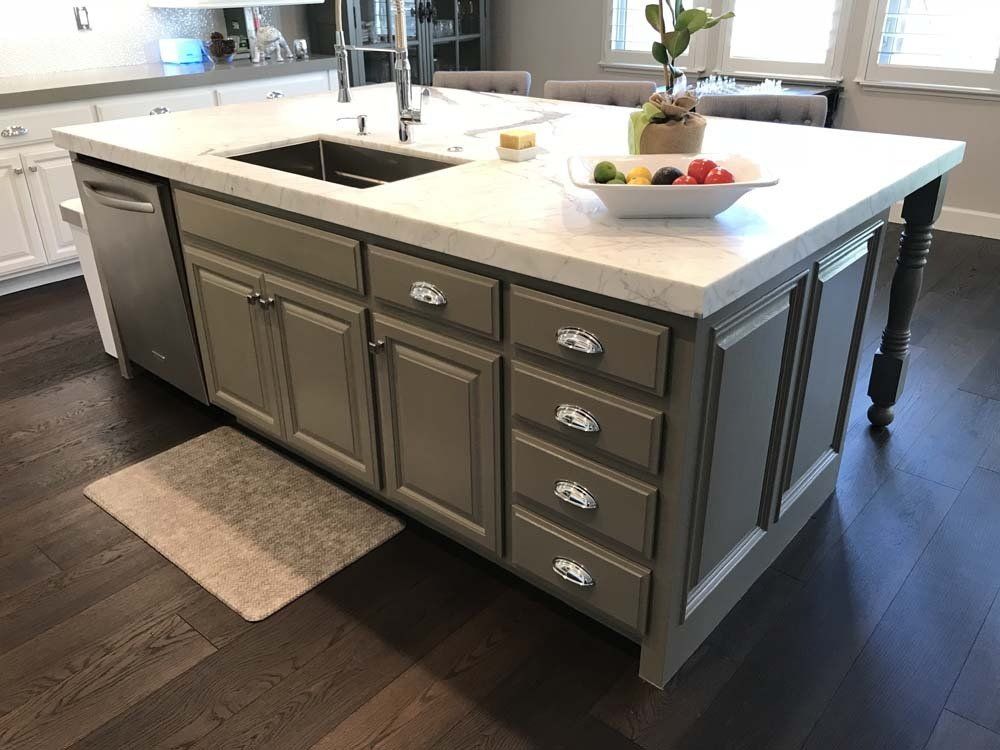 A kitchen island with a sink and a bowl of fruit on it.