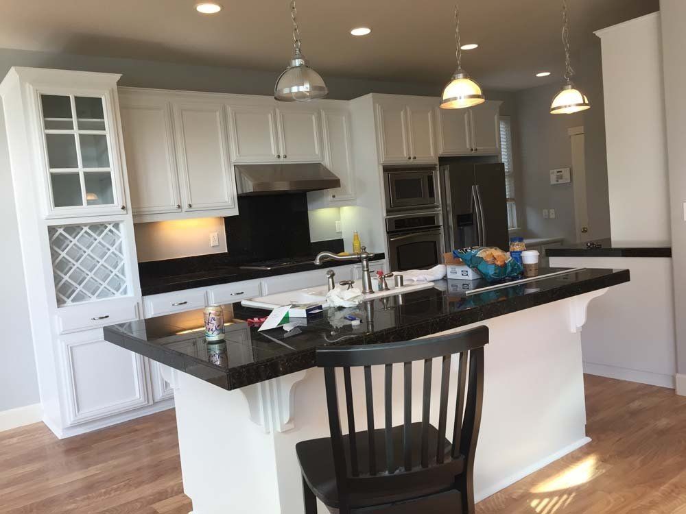 A kitchen with white cabinets and black counter tops