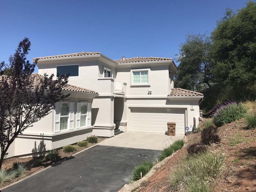 A large white house is sitting on top of a hill.