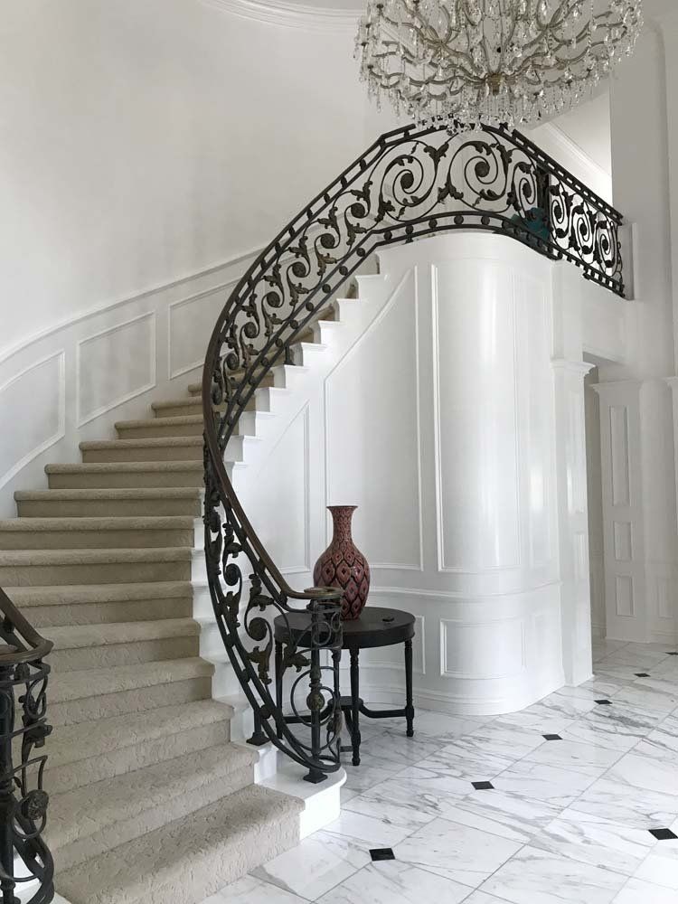 A spiral staircase with a wrought iron railing in a white room