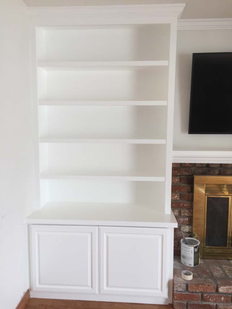 A living room with white shelves and a fireplace.