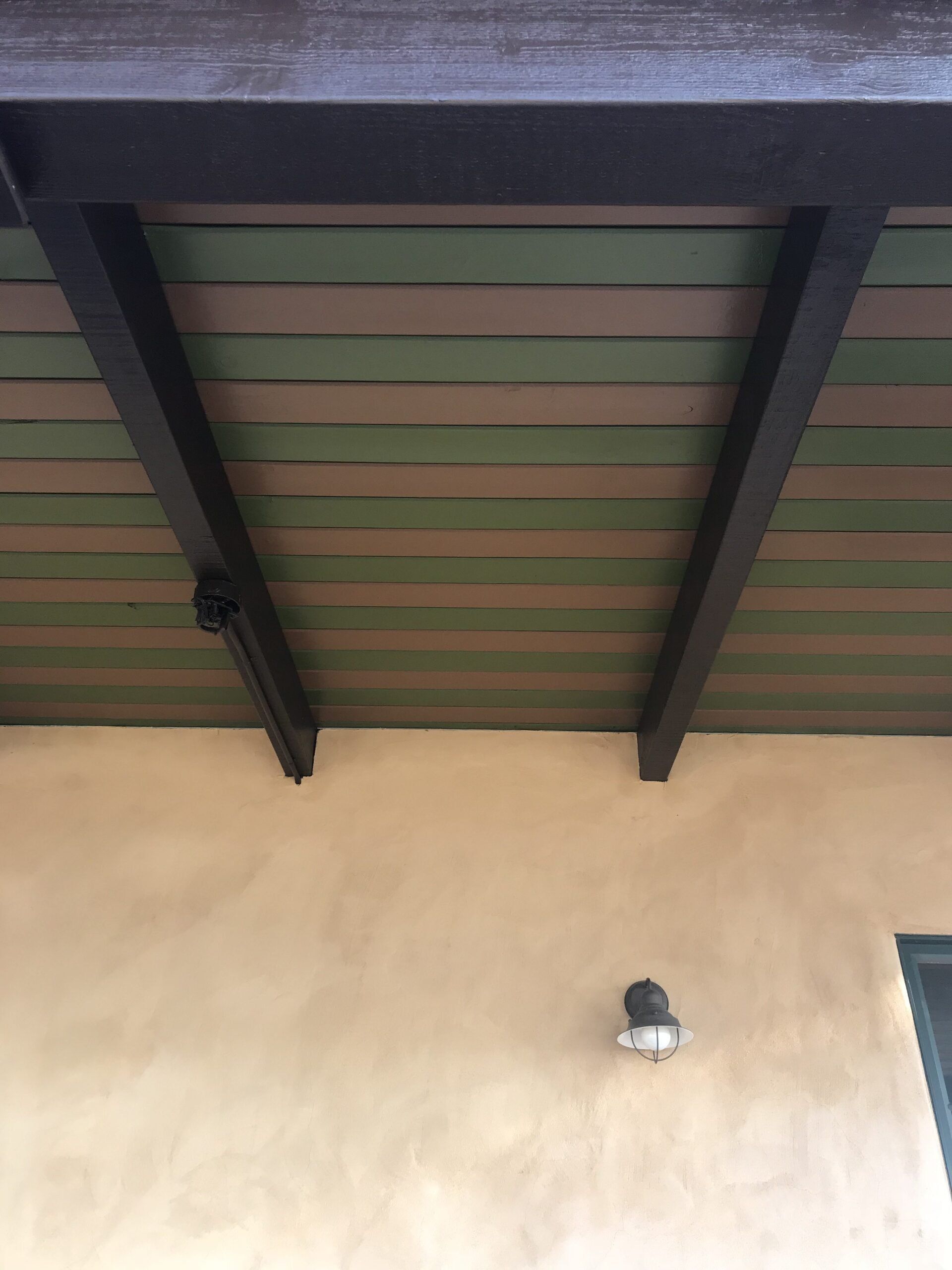 A ceiling with wooden beams and a light on the side of a building.