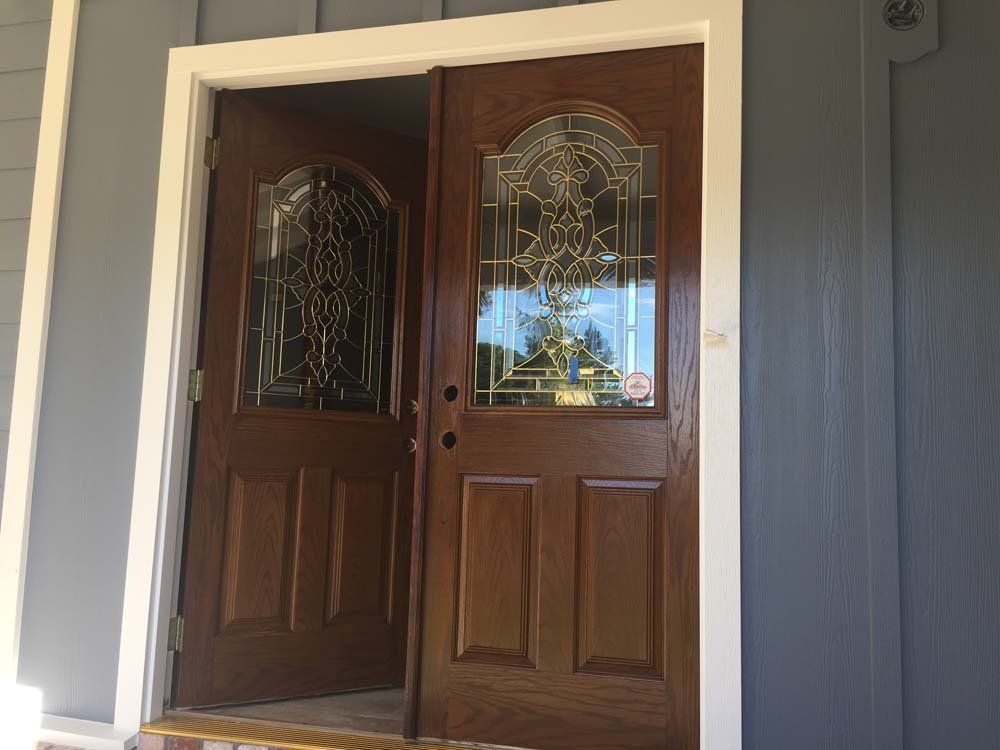 A pair of wooden doors with stained glass windows on a house.