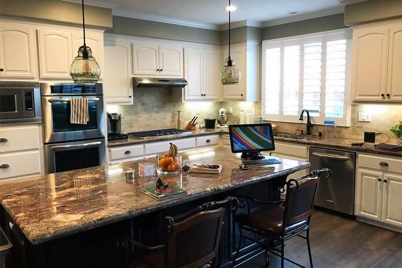 A kitchen with a large island and a computer on the counter.