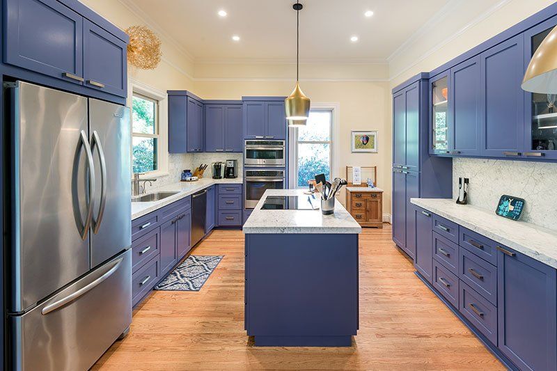 A kitchen with blue cabinets and stainless steel appliances.