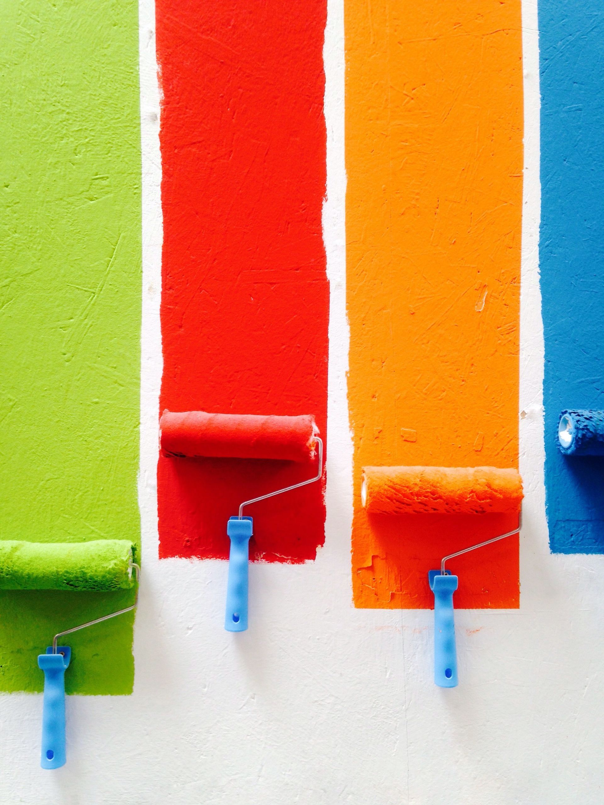 four paint rollers with different colors painted on a wall