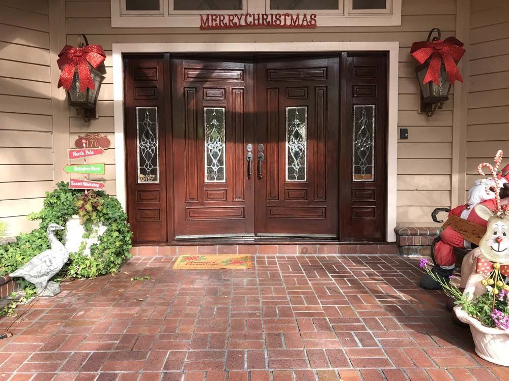 The front door of a house decorated for christmas with a sign that says merry christmas.