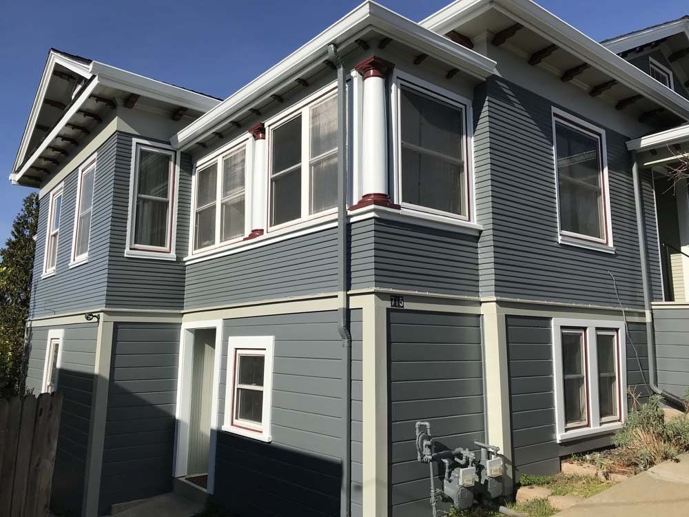 A large gray house with a lot of windows on a sunny day.