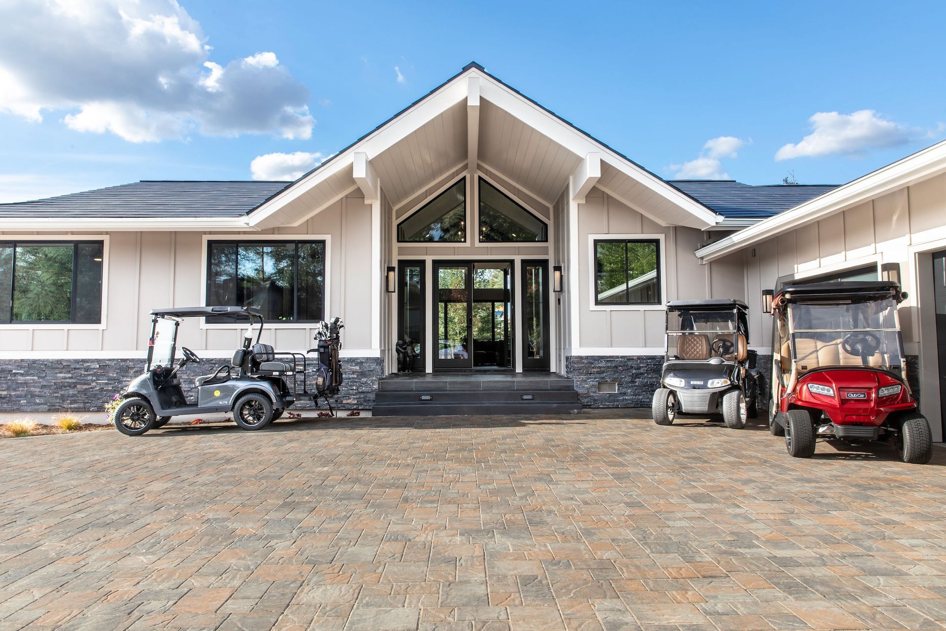 Three golf carts are parked in front of a large house.