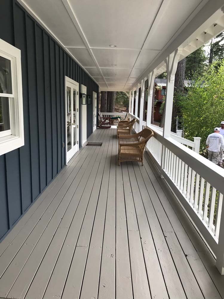 A long porch with chairs and a white railing