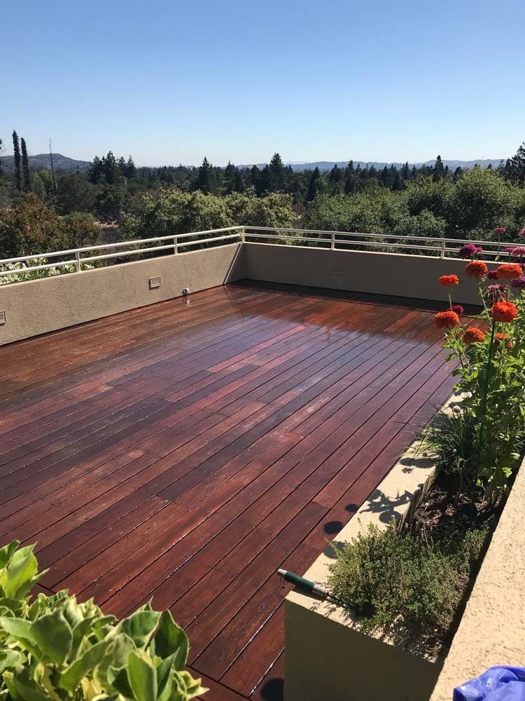 A wooden deck with flowers and trees in the background.