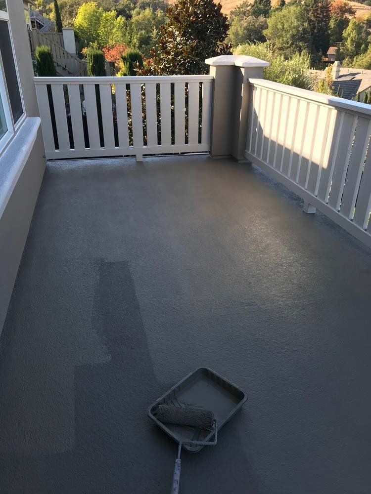 A paint roller is sitting on a tray on a balcony.