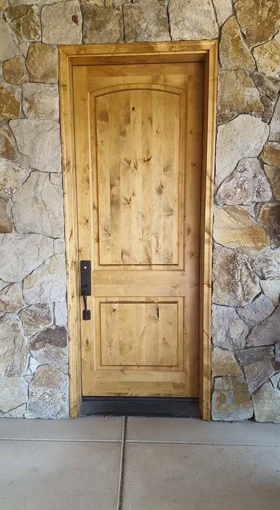 A wooden door is sitting in front of a stone wall.