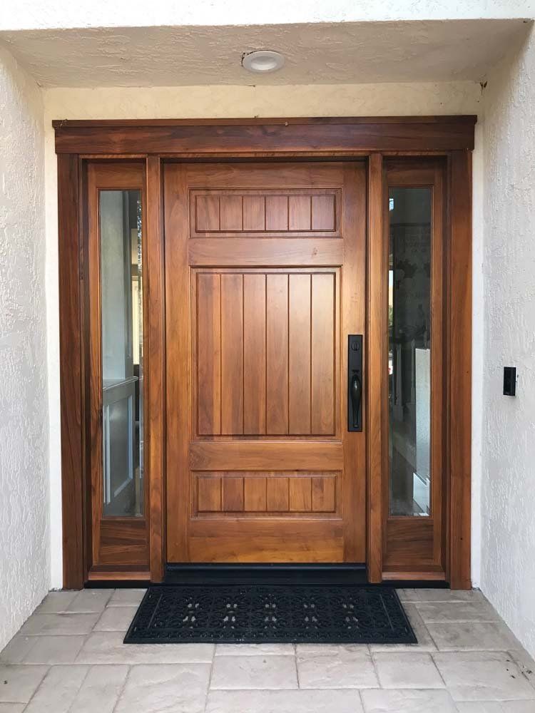 A large wooden door with a black mat in front of it