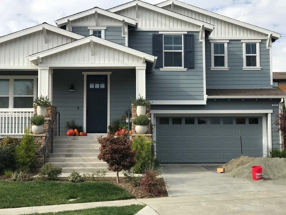 A large blue and white house with a black door and shutters.