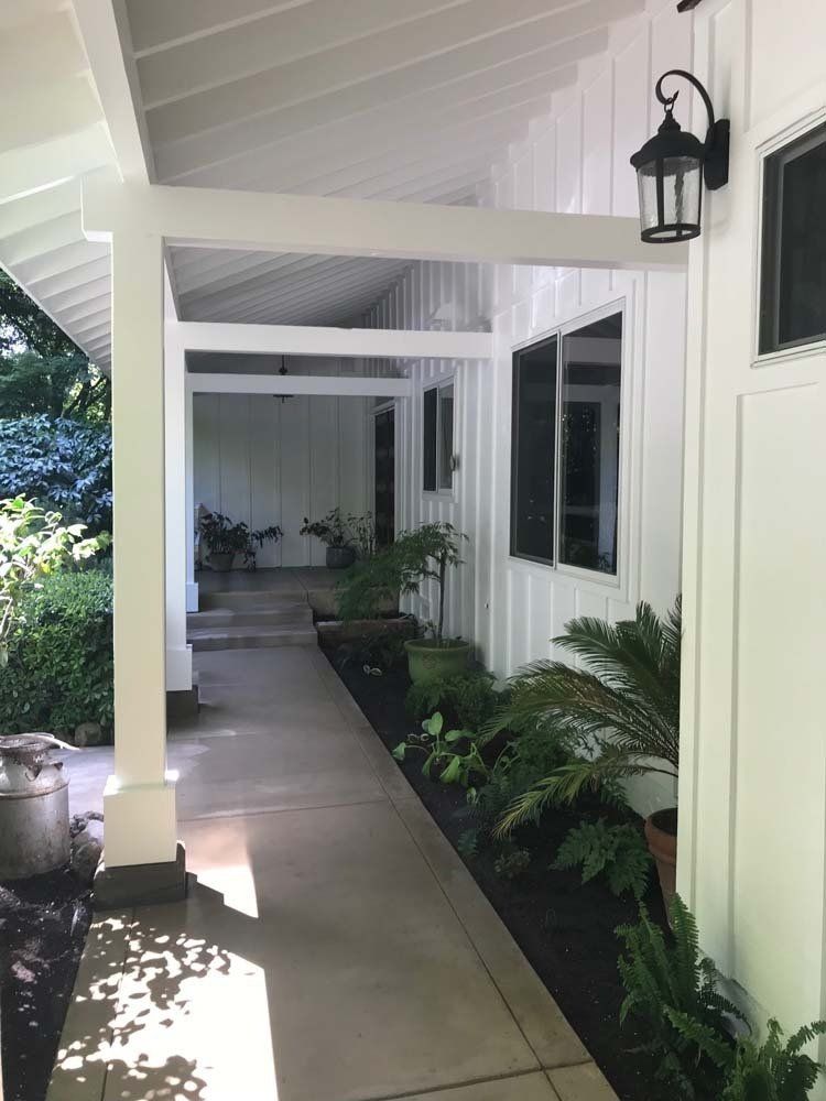 A white house with a covered walkway leading to the front door.
