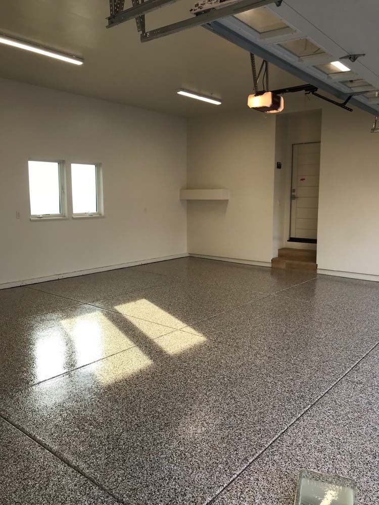An empty garage with a garage door opener and a window.