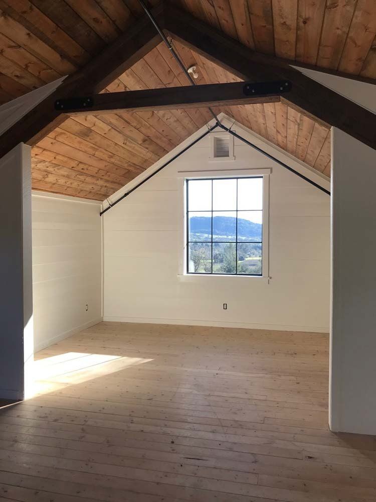 An empty room with a wooden ceiling and a window.