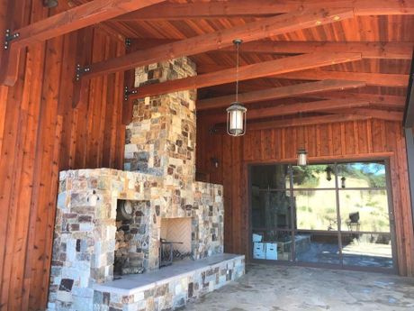 a large stone fireplace under a wooden roof