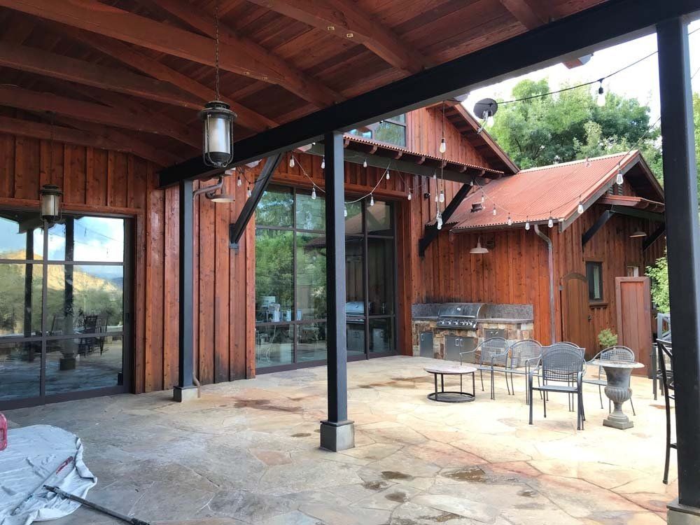A large wooden house with a patio area in front of it.