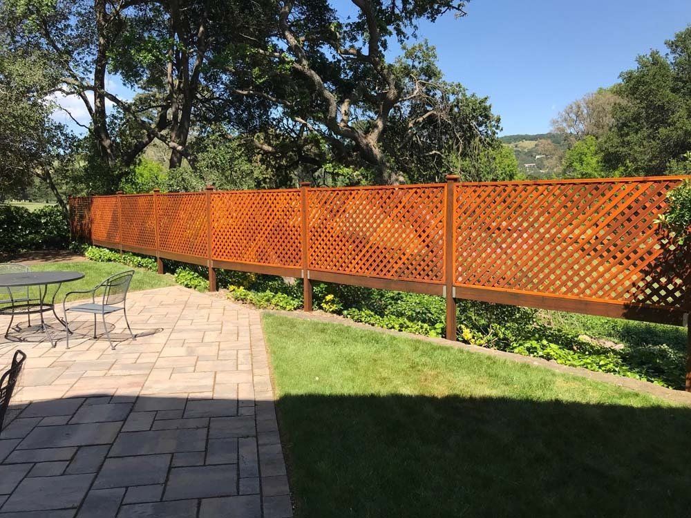 A wooden fence surrounds a patio with a table and chairs.