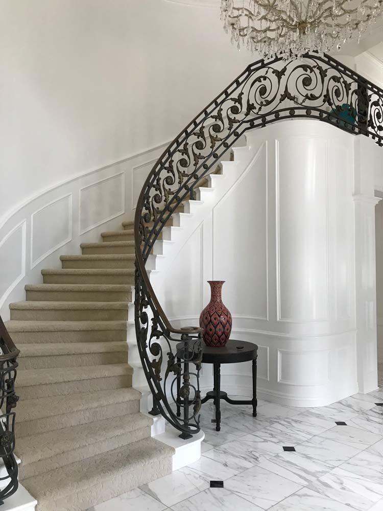 A staircase with a wrought iron railing and a vase on a table