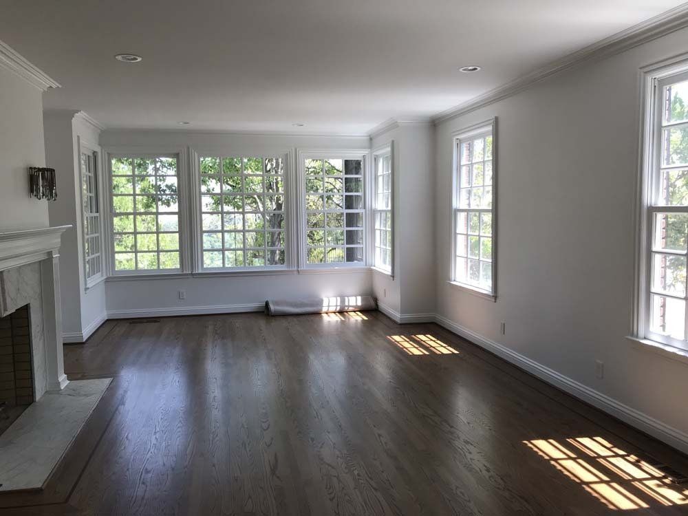 An empty living room with a fireplace and lots of windows