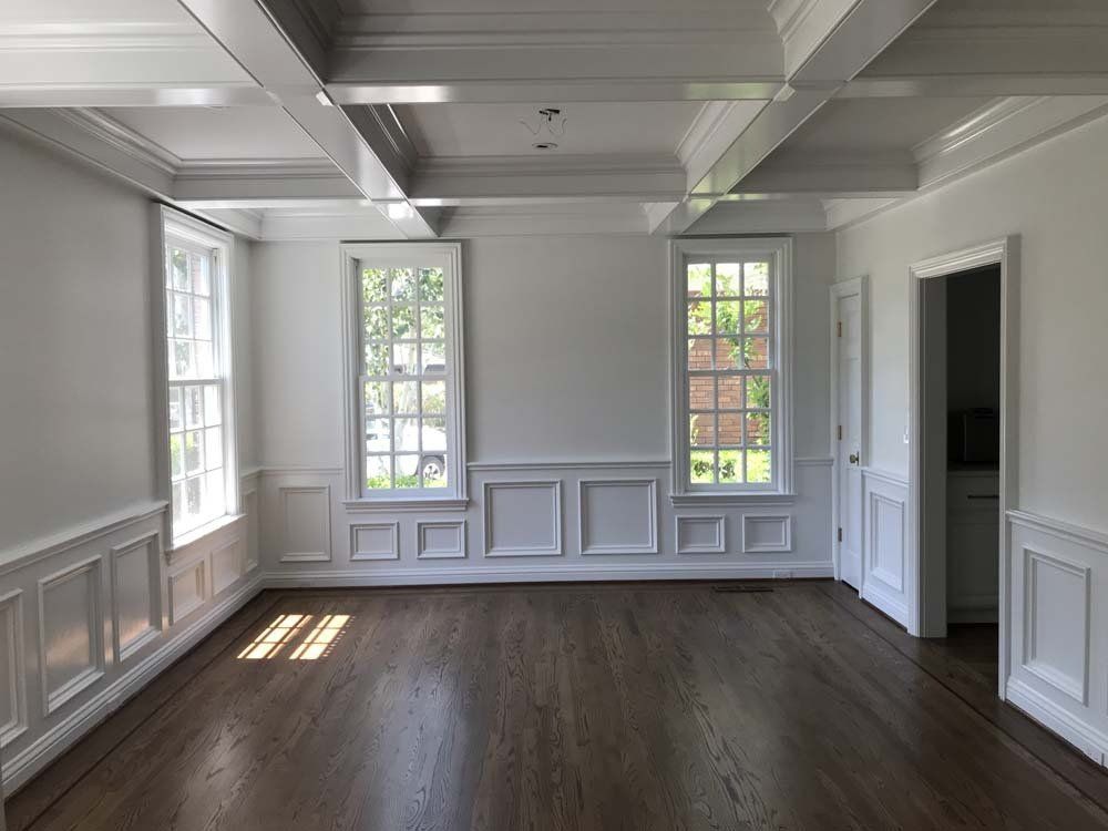 An empty living room with hardwood floors and white walls