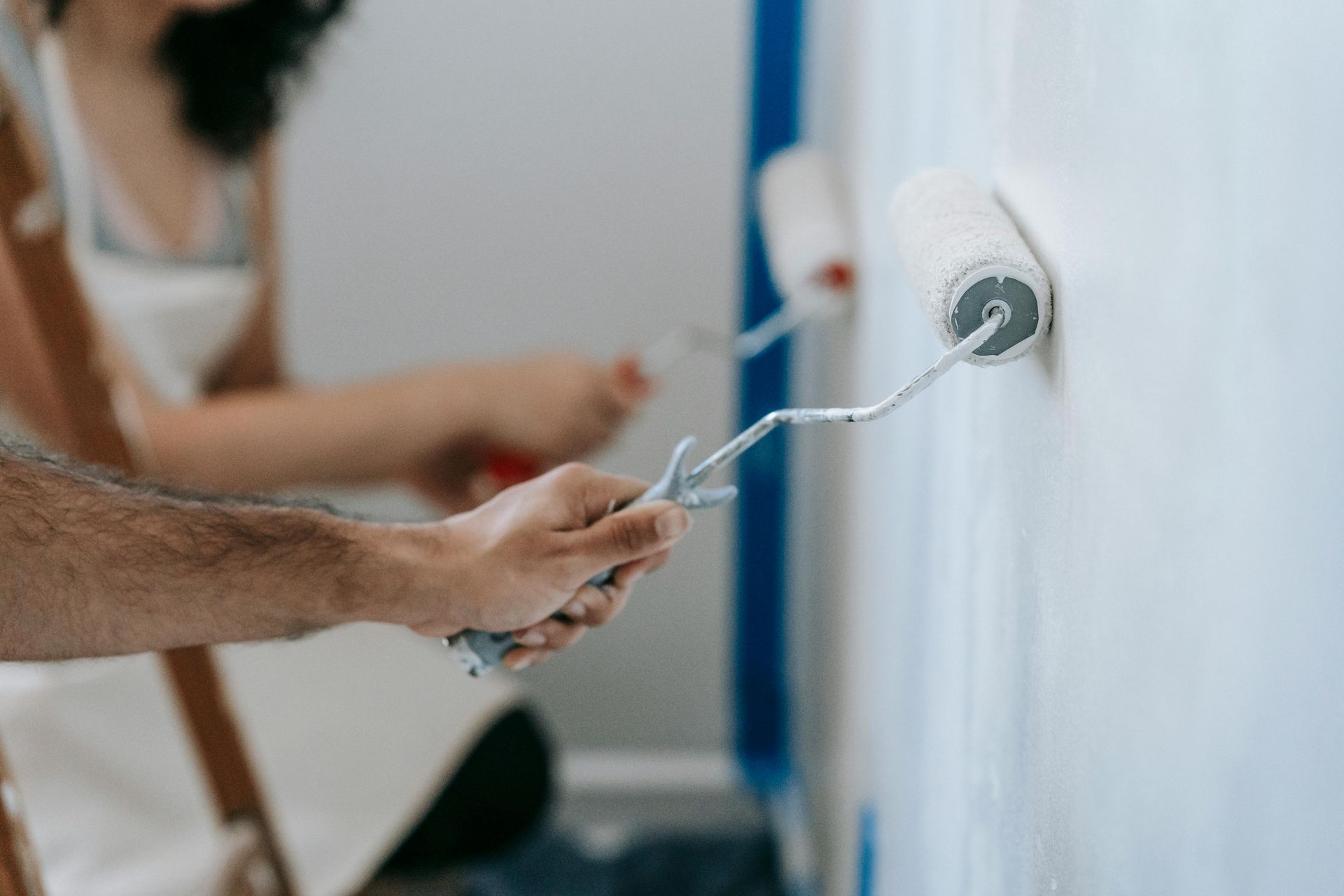 A man is painting a wall with a paint roller.