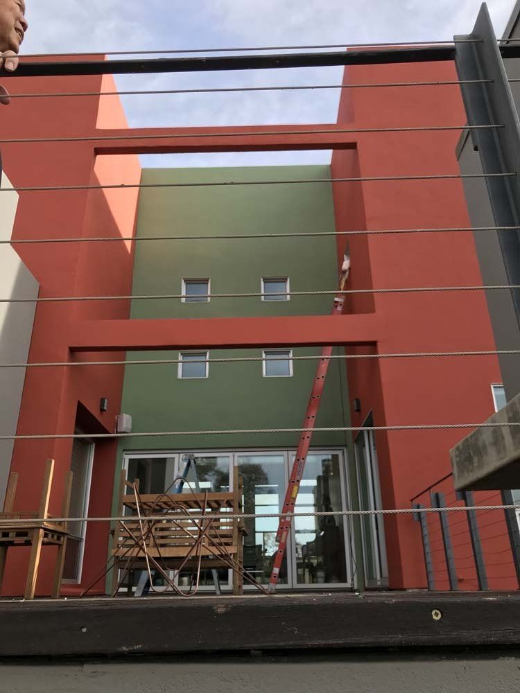 A red and green building with a stainless steel railing