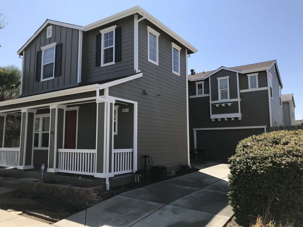 A house with a porch and a garage next to another house
